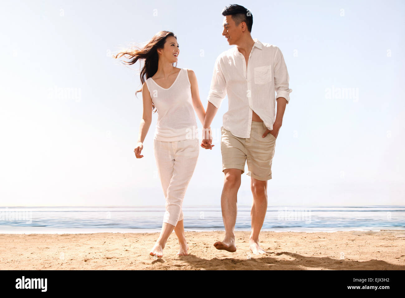 The romantic young lovers holding hands walking in the sea Stock Photo