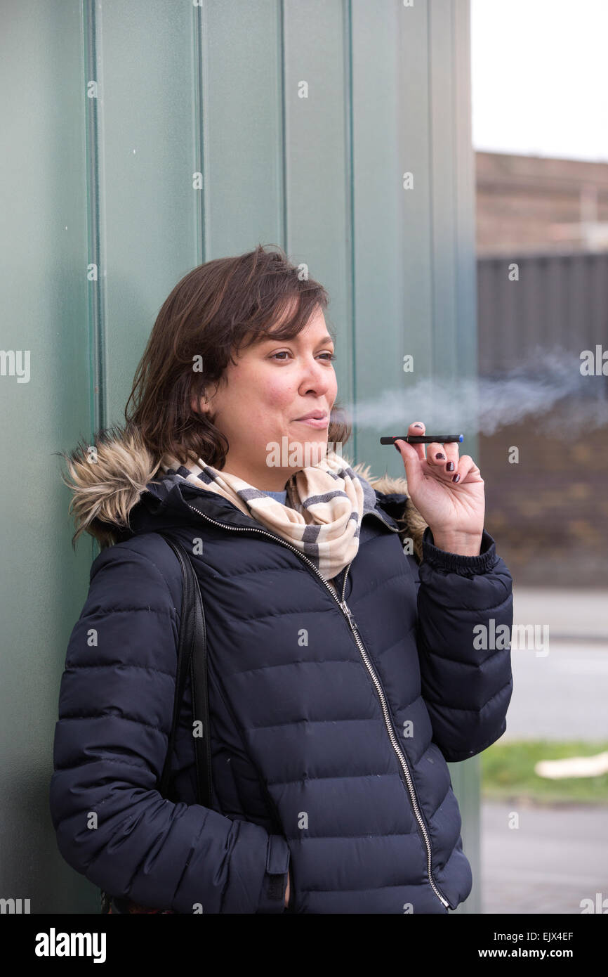 Woman smoking an e-cigarette outside an office building, UK Stock Photo