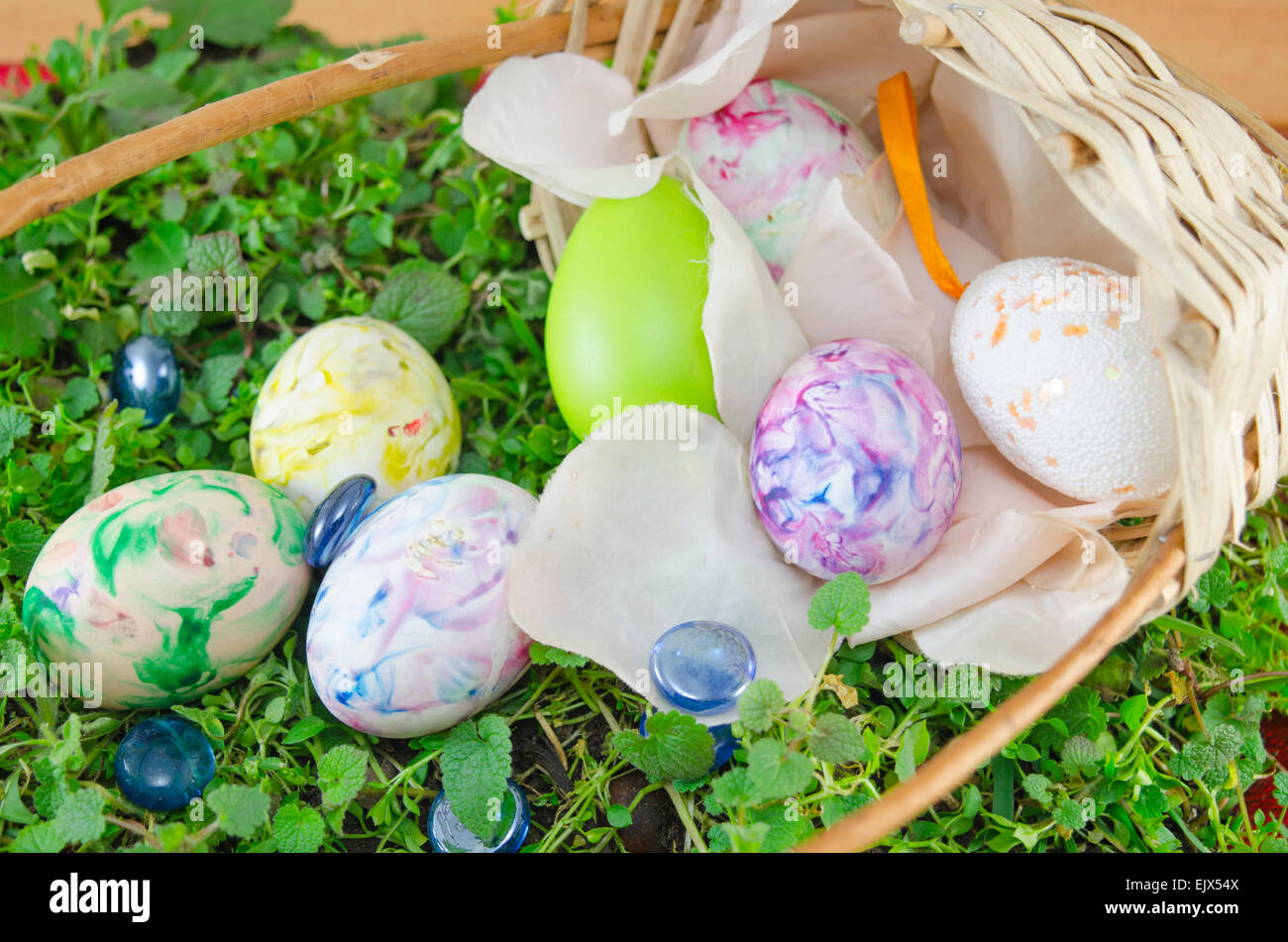 Basket full of hand colored Easter Eggs in decoupage placed on green grass surface Stock Photo