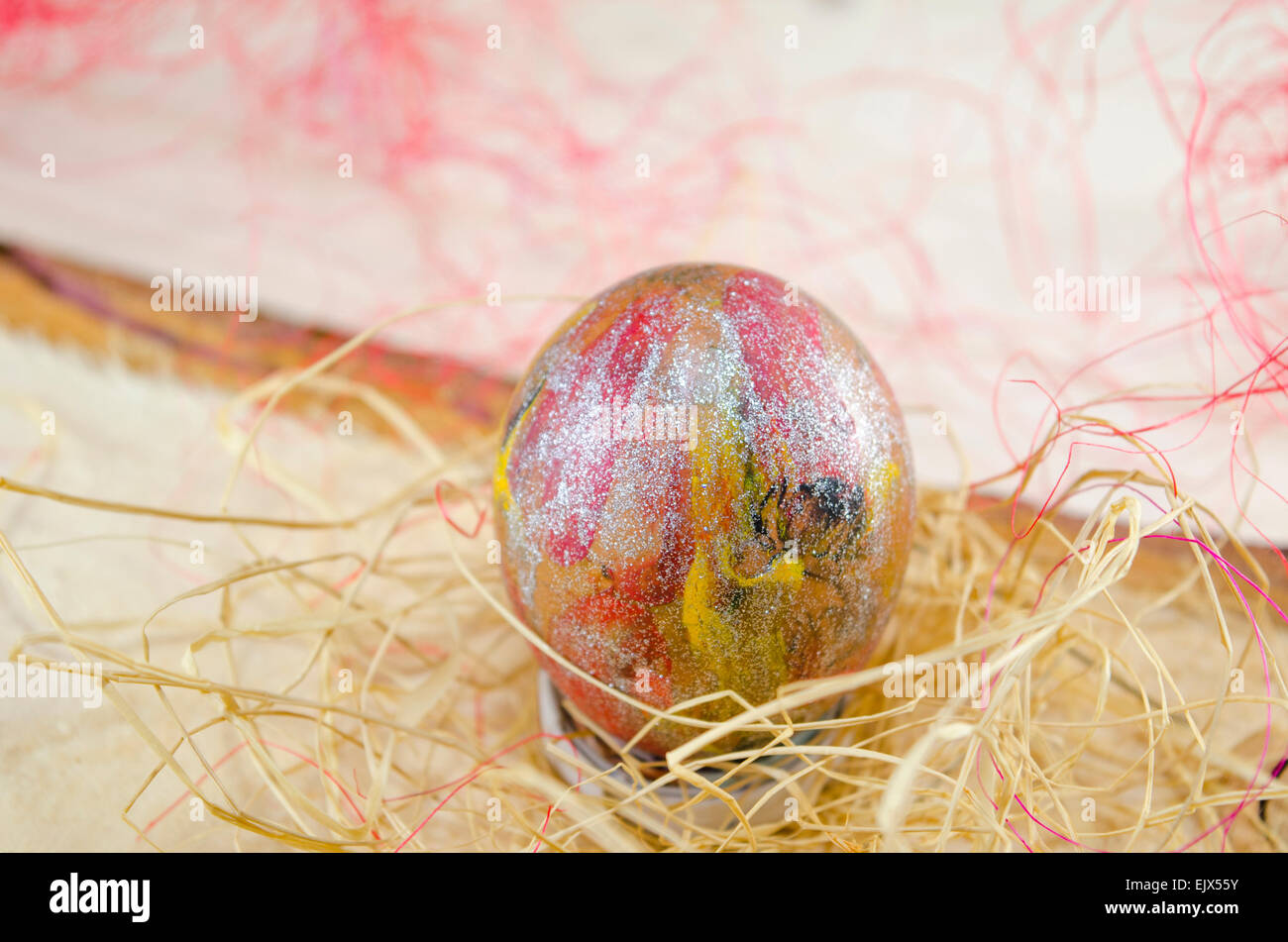 Hand painted reddish Easter egg on wooden table placed in a nest Stock Photo