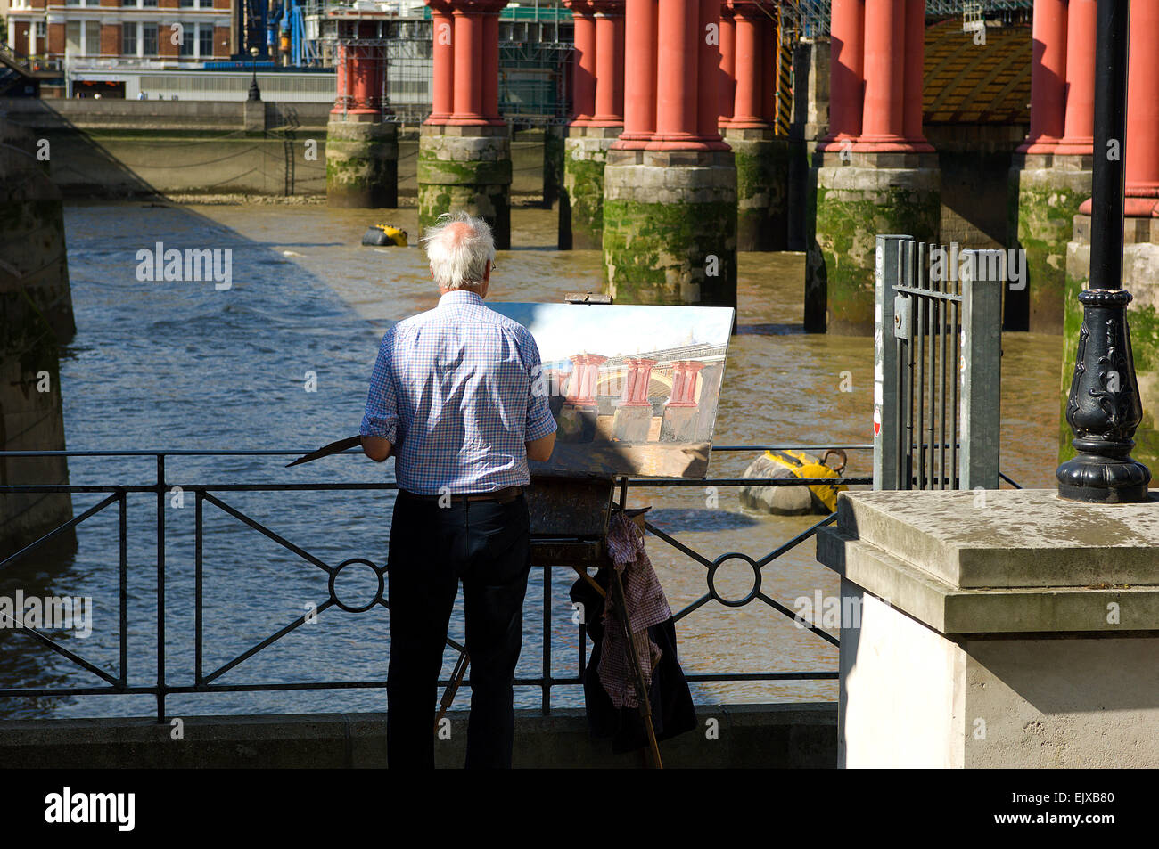 An artist working outdoors in London painting the old Blackfriars Bridge. Stock Photo