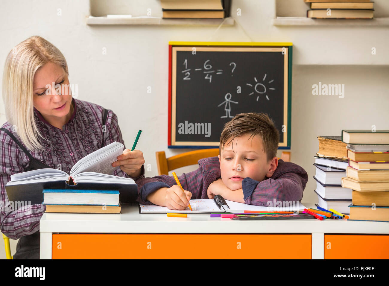 Tutor teaches a school Boy with his studies. Stock Photo