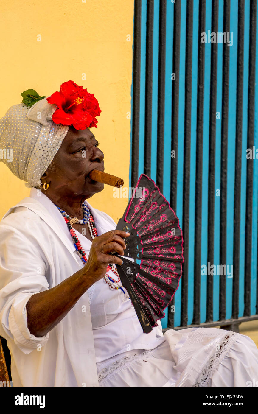 Cuba, Havana, portrait of woman with   cigar and fan wearing traditional costume Stock Photo