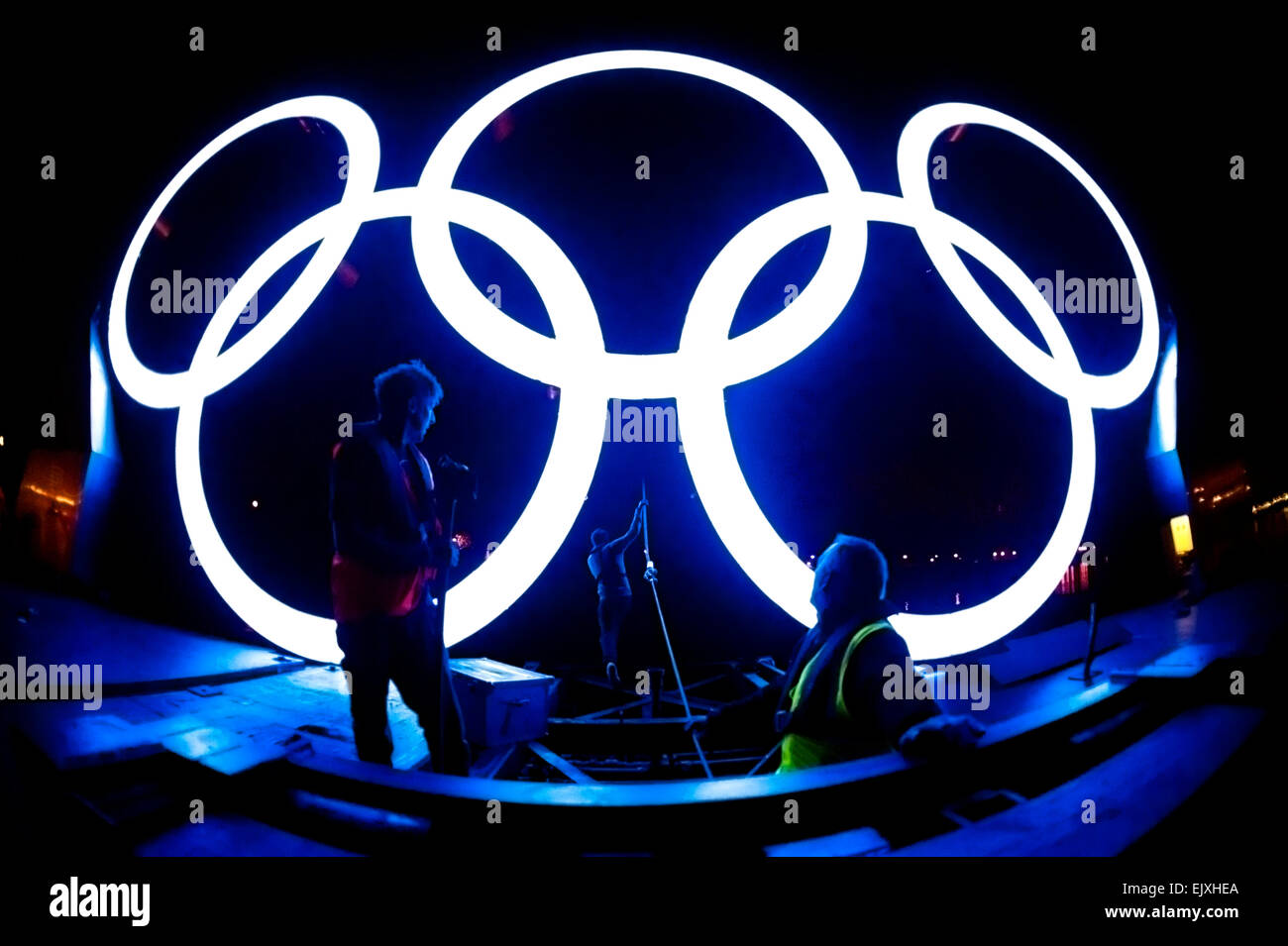 The Olympic Rings illuminate workers installing the interactive, 'Rings on the River' exhibit, during the London Olympic Games 2012. England. Stock Photo