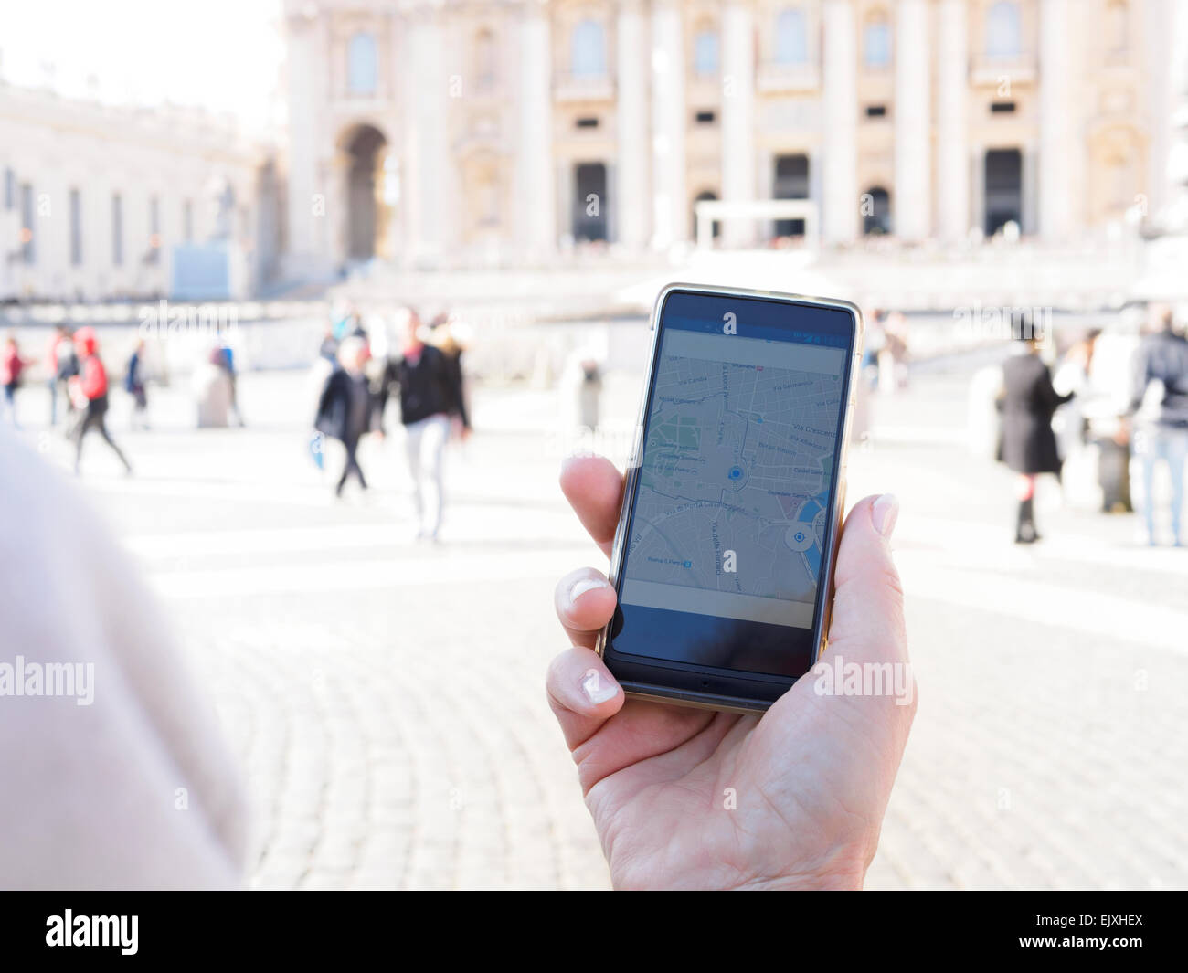 Italy, Rome, Woman holding mobile with GPS at Piazza di San Petro Stock Photo