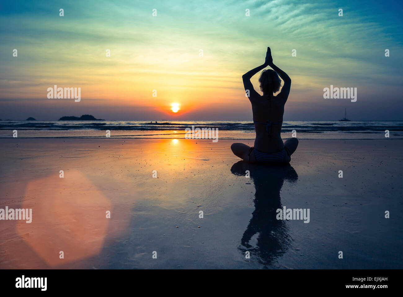Female silhouette in Yoga meditation pose at amazing sunset Stock Photo ...