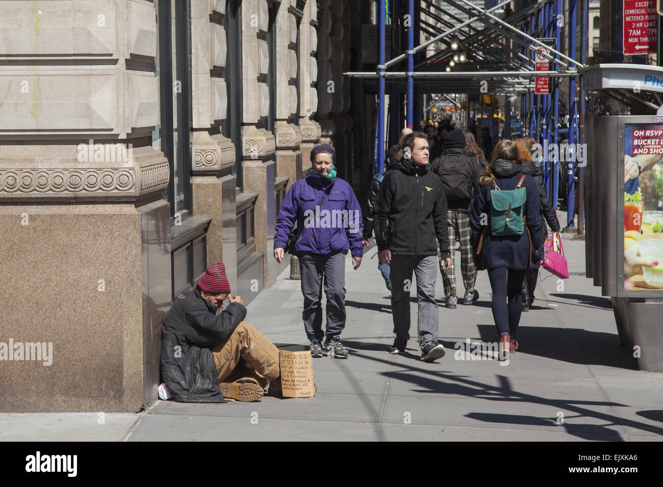 Man with sign saying he's a homeless veteran, a plummer by trade and needs a helping hand. 5th Ave. NYC. Stock Photo