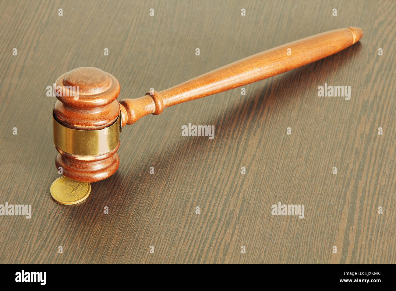 Auction hammer or judge gavel and one dollar coin on wooden table taken closeup. Stock Photo