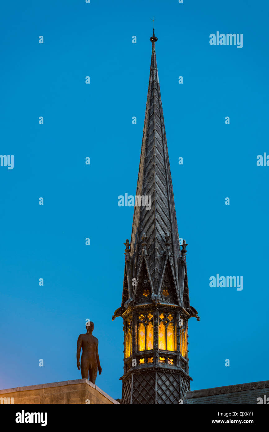 The spire of Exeter College chapel, Oxford University and Antony Gormley's sculpture The Iron Man at dusk Stock Photo