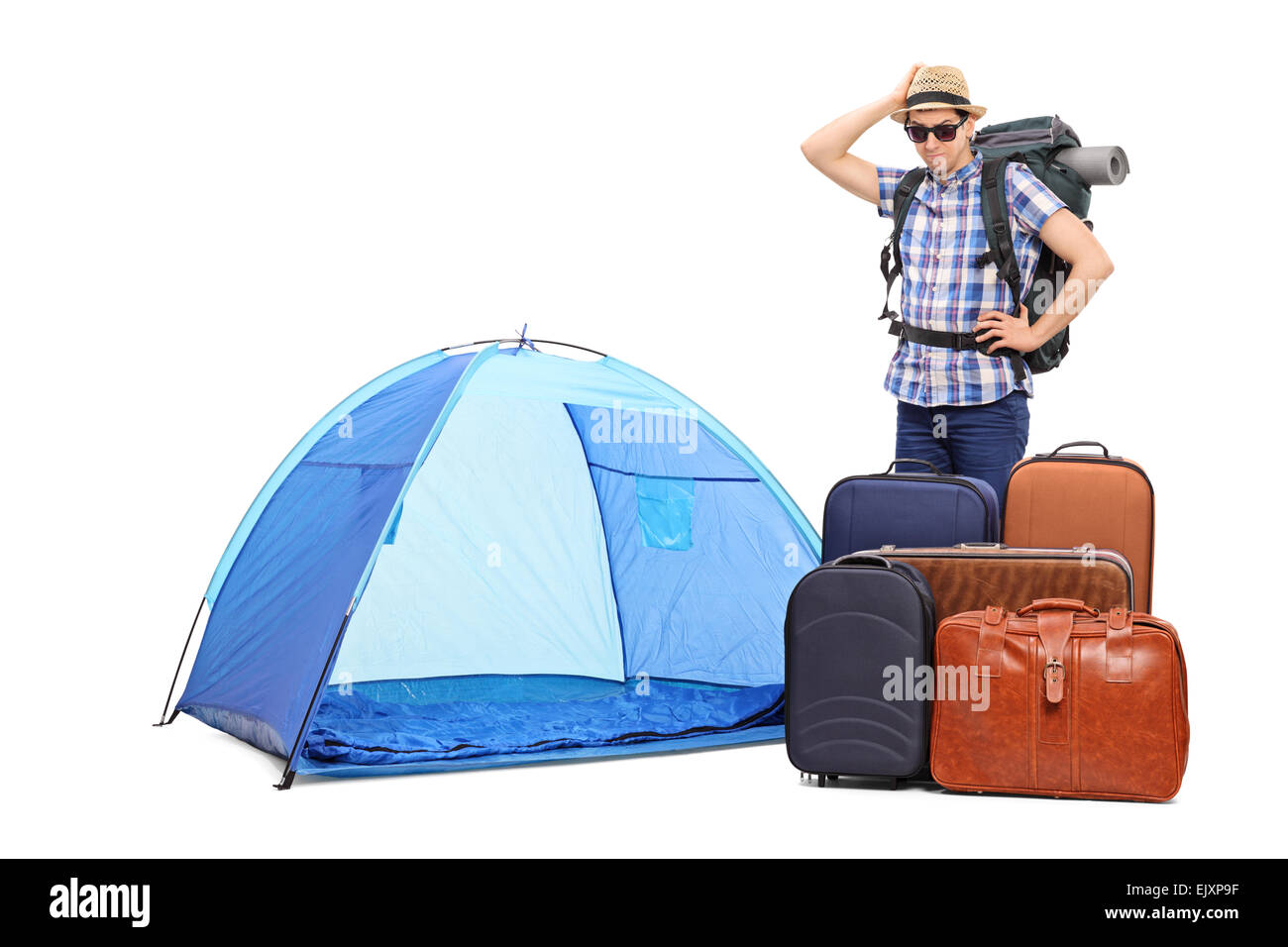 Baffled male tourist standing next to a tent and five huge briefcases isolated on white background Stock Photo