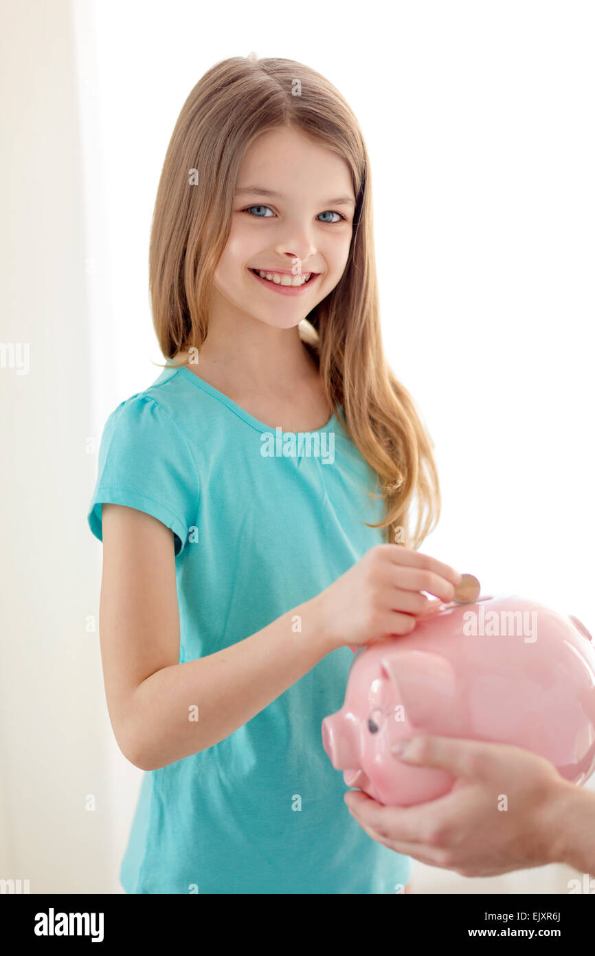 smiling little girl putting coin into piggy bank Stock Photo - Alamy
