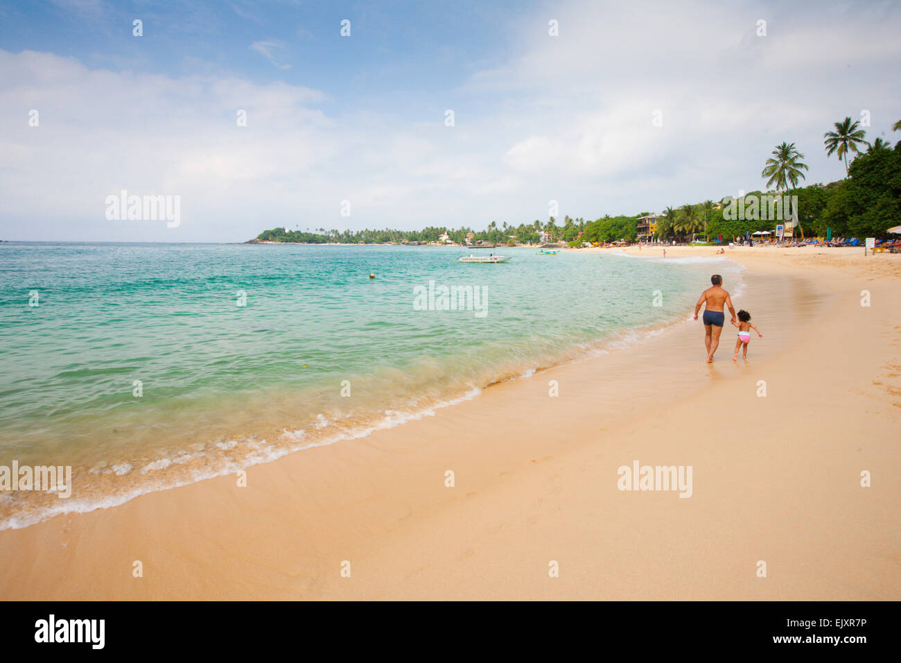 FATHER AND DAUGHTER WALKING ON UNAWATUNA BEACH Stock Photo