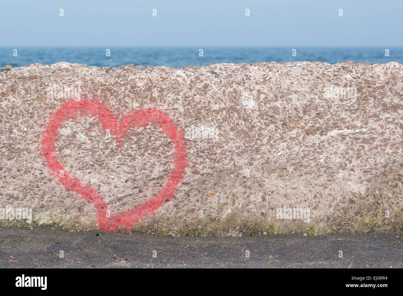 Red heart spray painted on wall in background of the sea Stock Photo