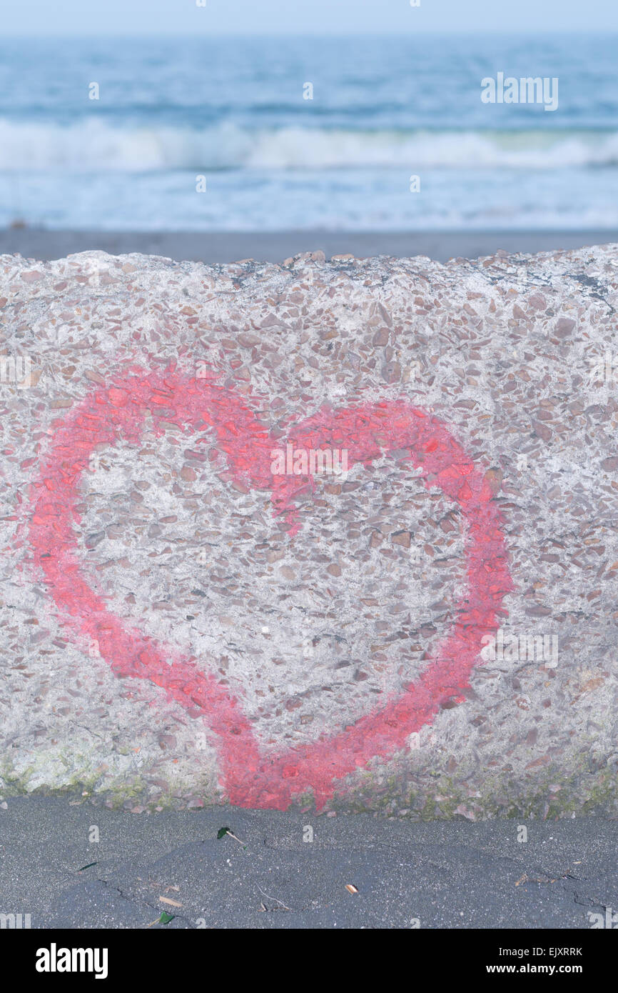 Red heart spray painted on wall in background of the sea Stock Photo