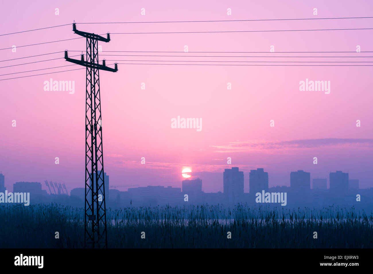 Power pole silhouettes in red purple cloudy sunset background, dark photo, dramatic, city scene Stock Photo
