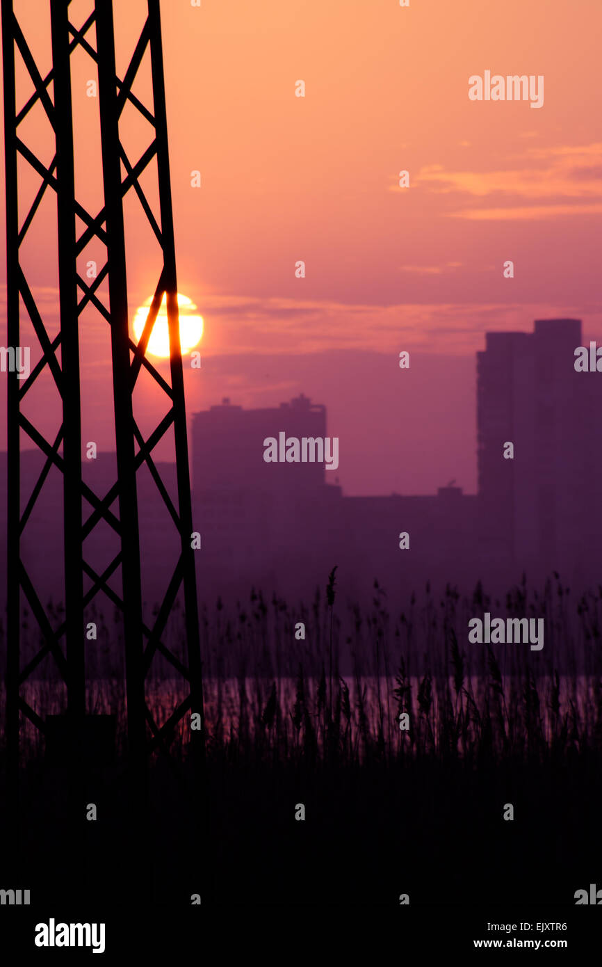 Electric pole silhouettes in red purple cloudy sunset background, dark photo, dramatic, city scene Stock Photo
