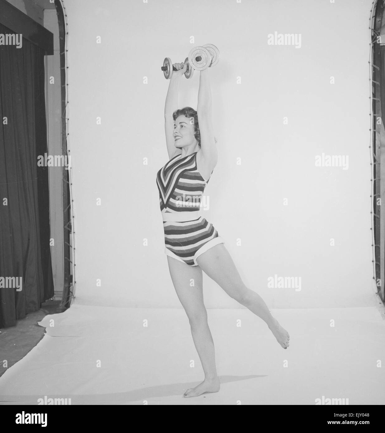 Reveille " Keep Young and Beatiful feature, Woman wearing one piece bathing costune exercising with weights Circa 1958 Stock Photo