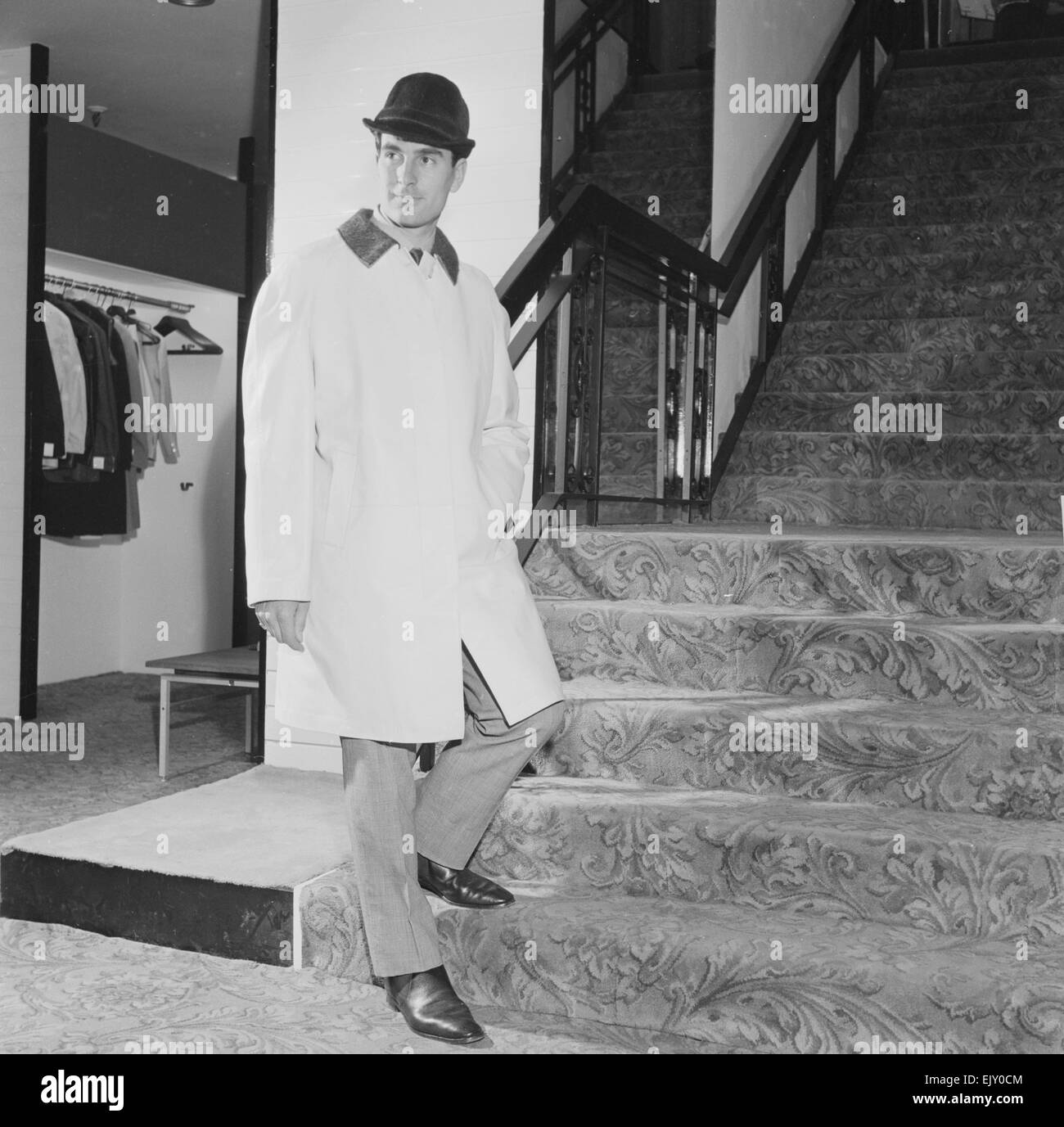 Reveille Men's Fashions of the Future shoot. Man wearing raincoat and hat on stairs . Circa 1960 Stock Photo
