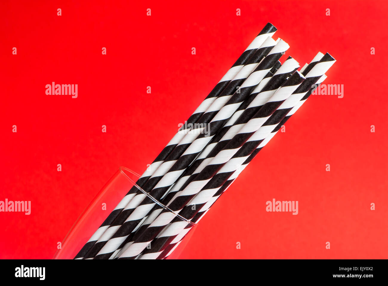 Striped black and white straws on red background Stock Photo