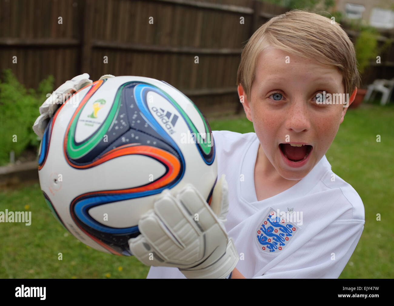 a child playing football in the garden wearing his England football kit Stock Photo