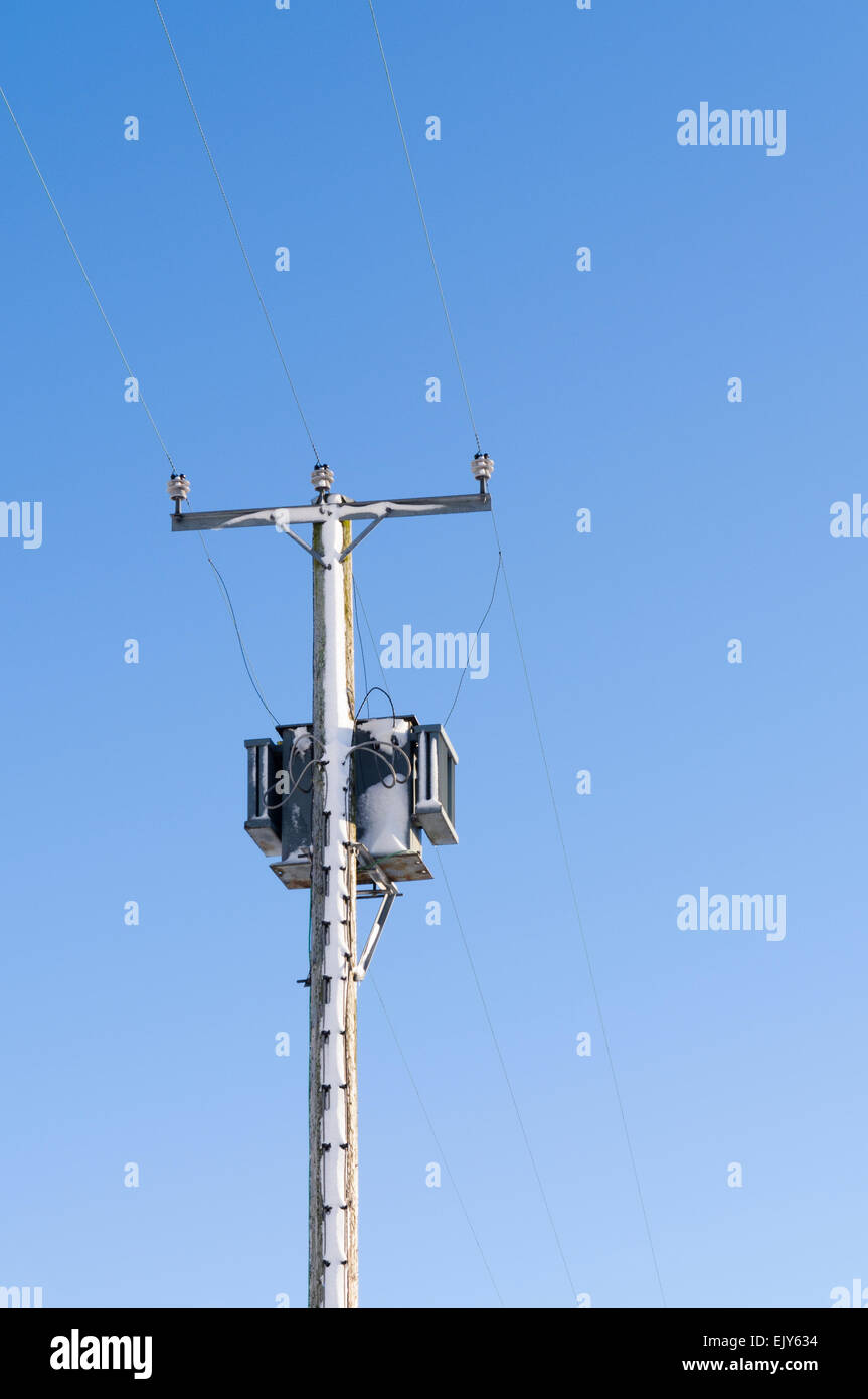 A 15kVA electrical transformer and power line covered with snow Stock Photo