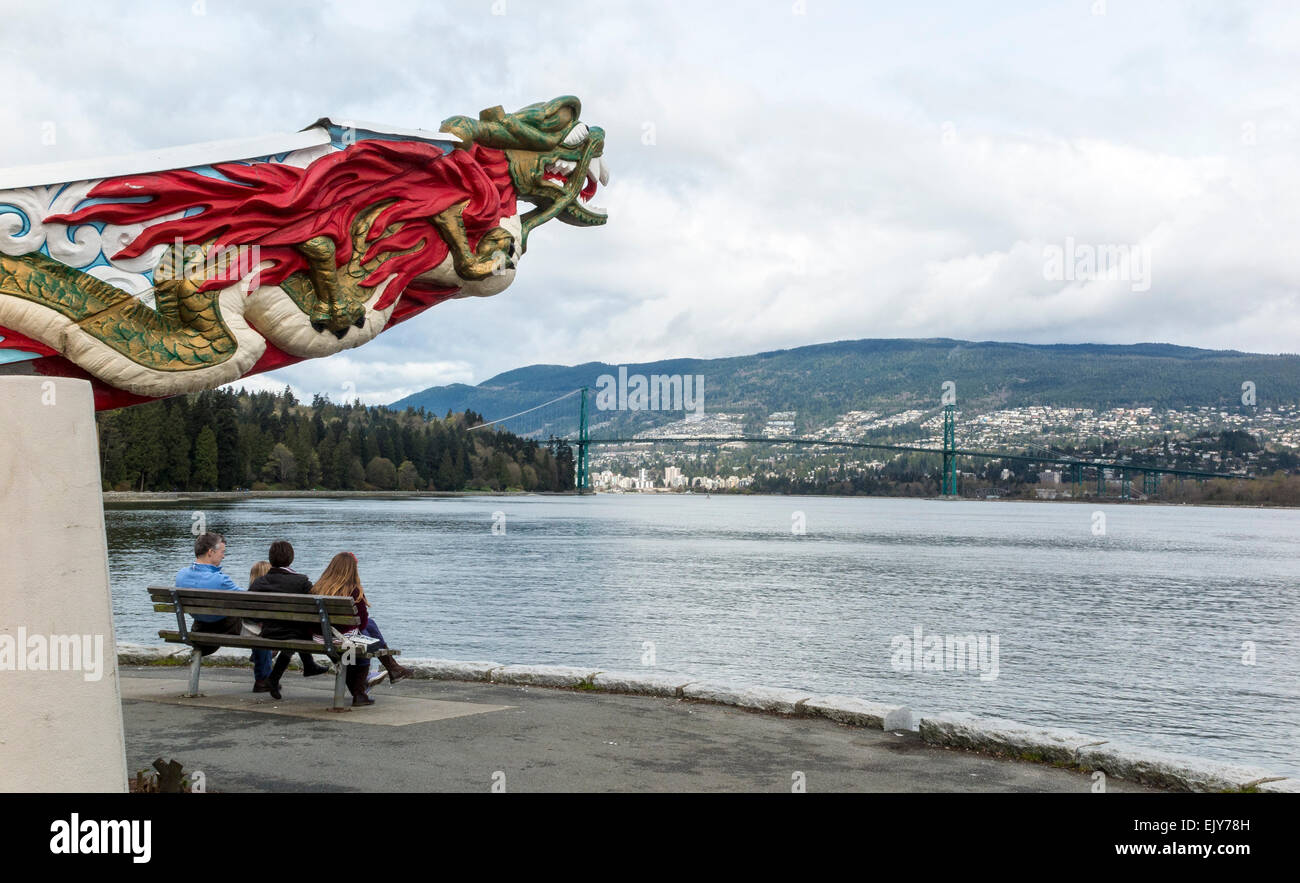 People resting on bench with Chinese sculpture along the seawall of Stanley Park, Vancouver, British Columbia, Canada. Stock Photo