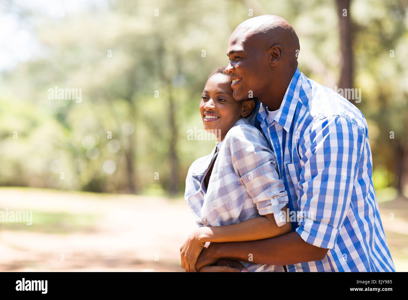 Cute asian couple sitting in the park smiling and looking at