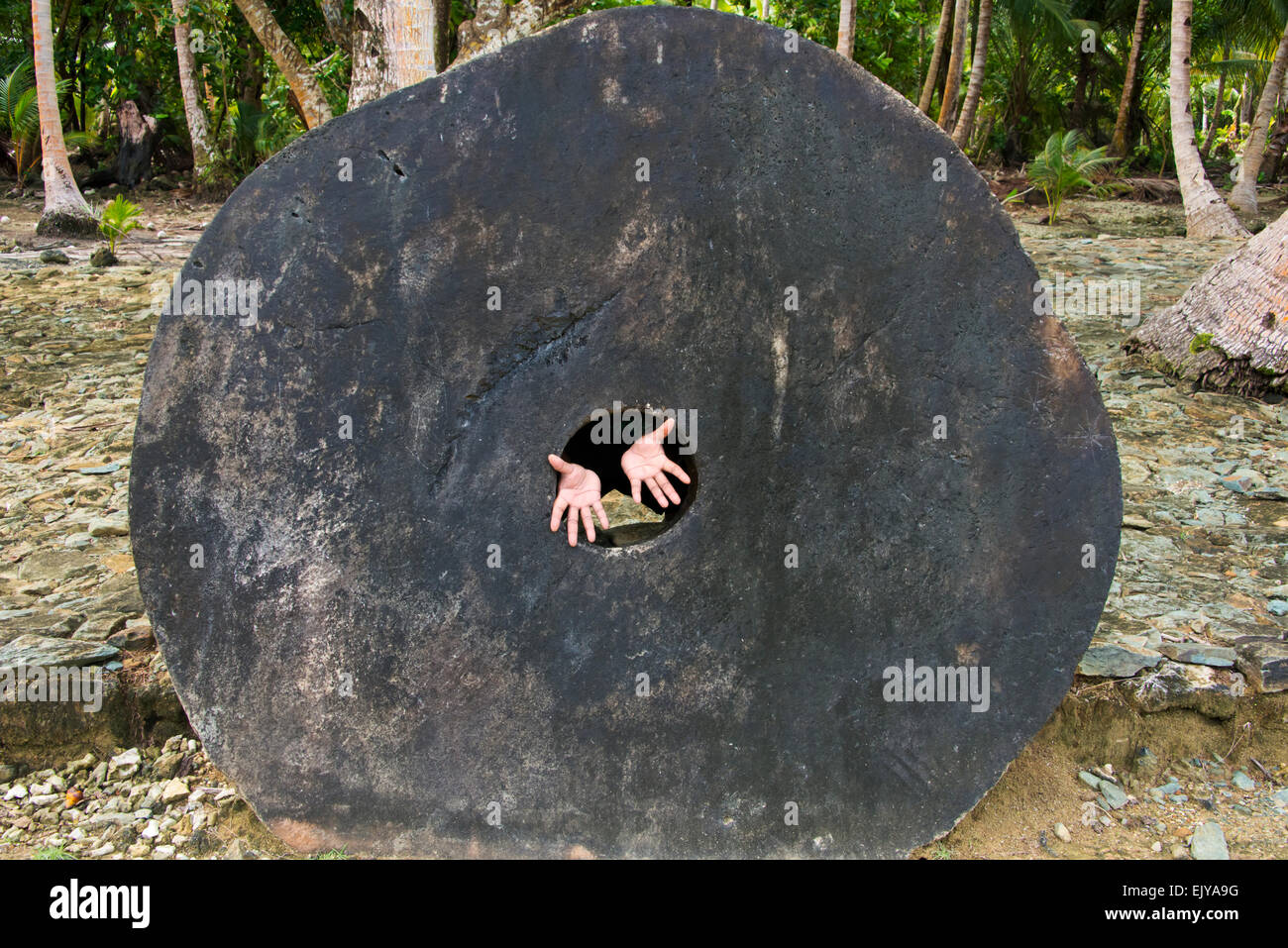 Stone money (Rai stones) in the bank, hands extending from the hole in the disc, Yap Island, Federated States of Micronesia Stock Photo