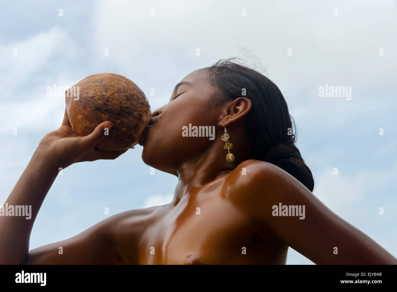 Yapese girl drinking from coconut, Yap Island, Federated States of Micronesia Stock Photo