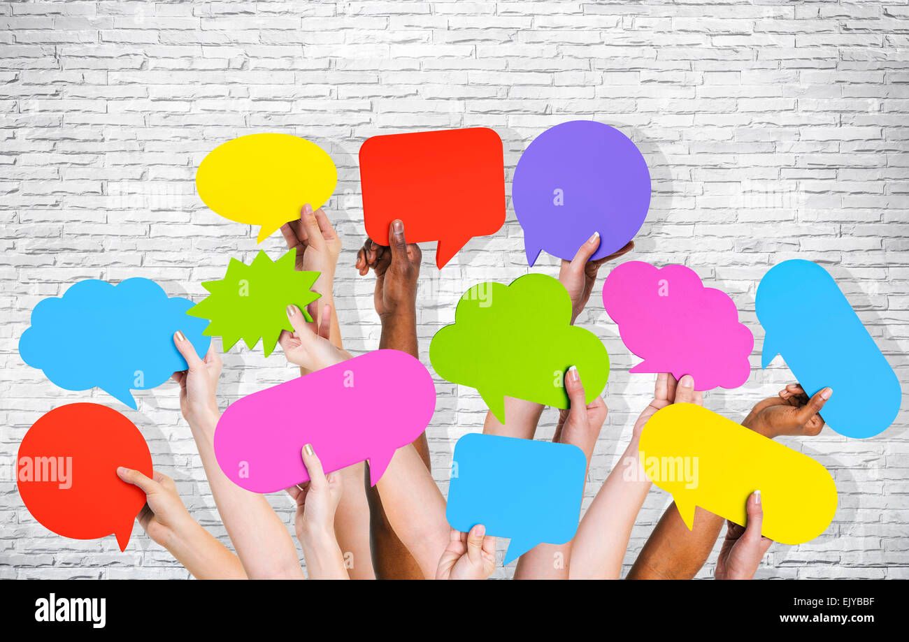 Group of human arms raised with speech bubble by brick wall. Stock Photo