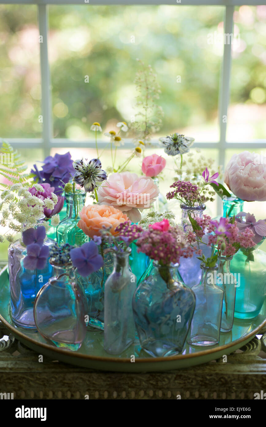 Floral Arrangement Of Cut Flowers In Blue Bottles Including Roses Stock Photo Alamy