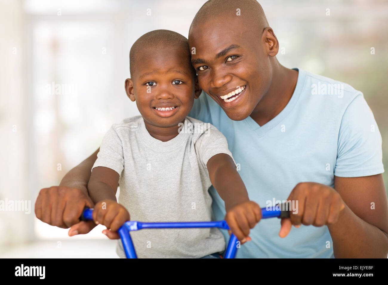 loving African American father teaching son to ride a bicycle Stock Photo