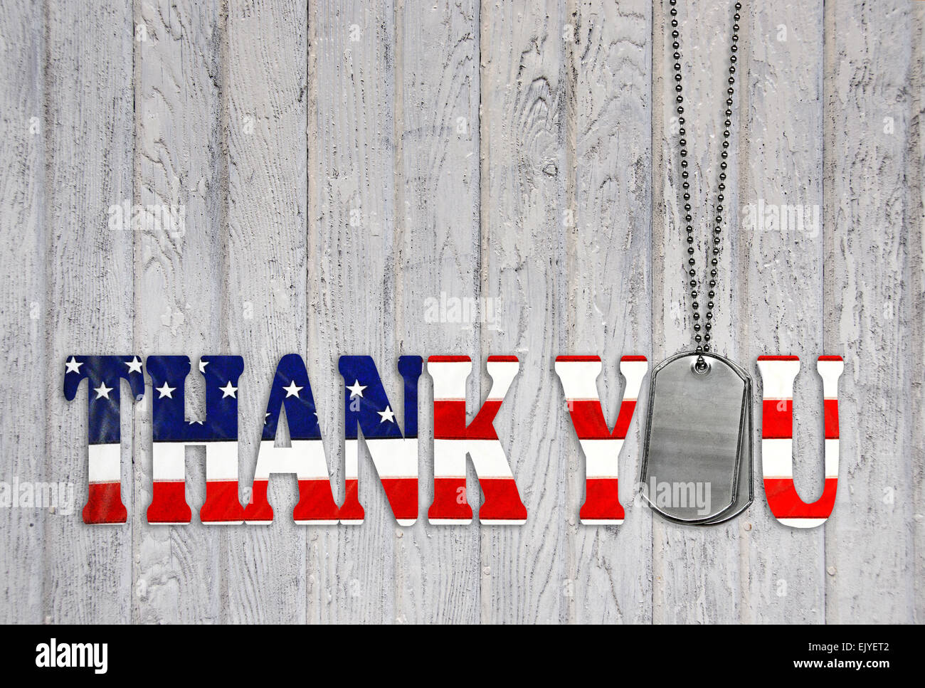 Military dog tags with thank you flag on weathered gray wood background. Stock Photo