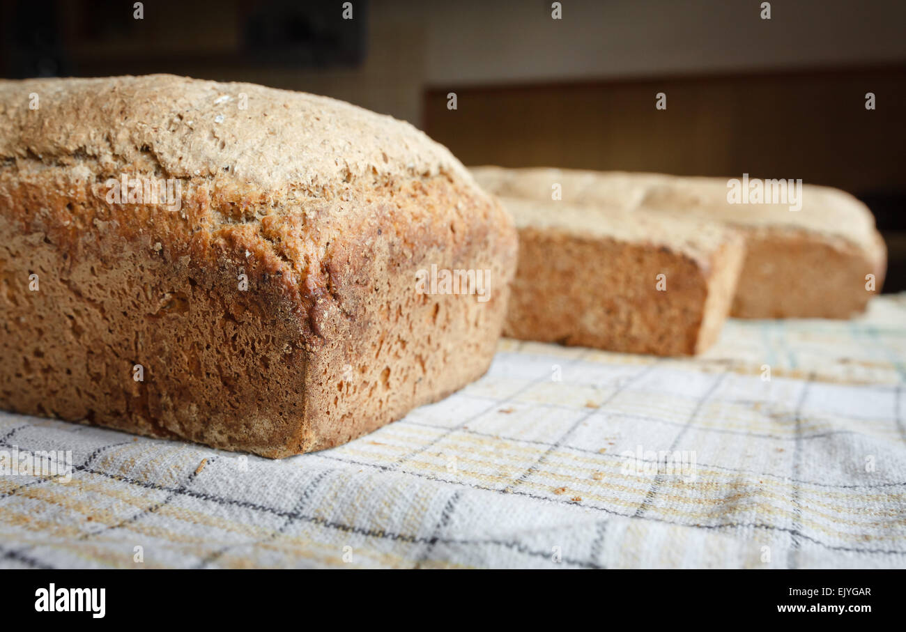 Homemade wholewheat loaf of bread close up on kitchen cloth as Christianity symbol, selective focus Stock Photo