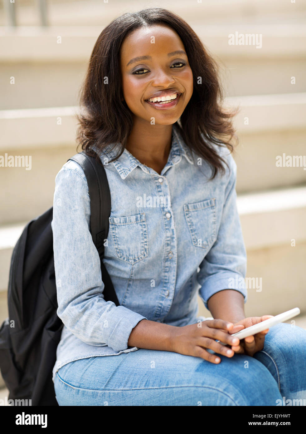 portrait of happy young African college student holding cell phone ...