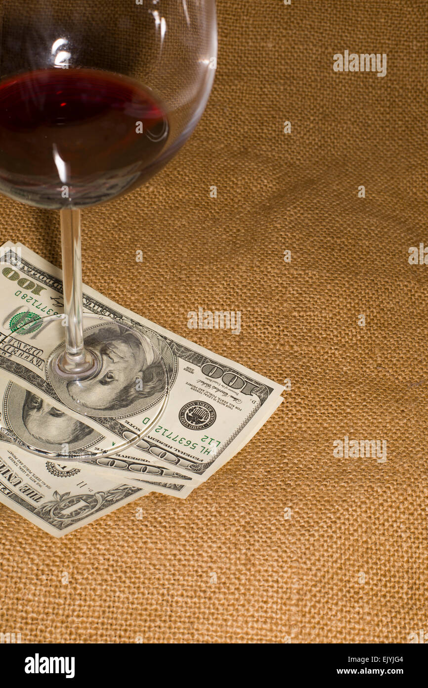 Glass of wine and a few US 100 dollars banknotes on the old tissue Stock Photo