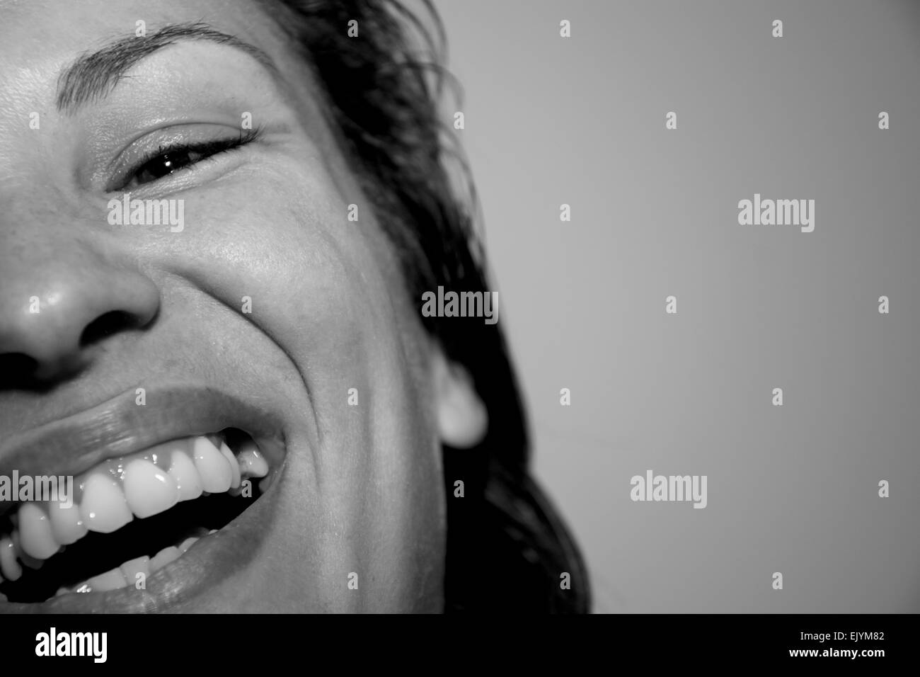 Closeup portrait of a pretty young woman laughing out loud monochrome indoors Stock Photo