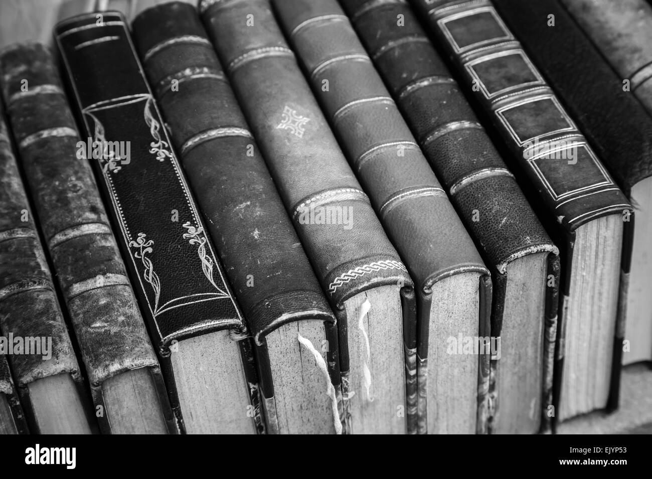 Old books with leather covers lay on the shelf, vintage stylized monochrome photo Stock Photo