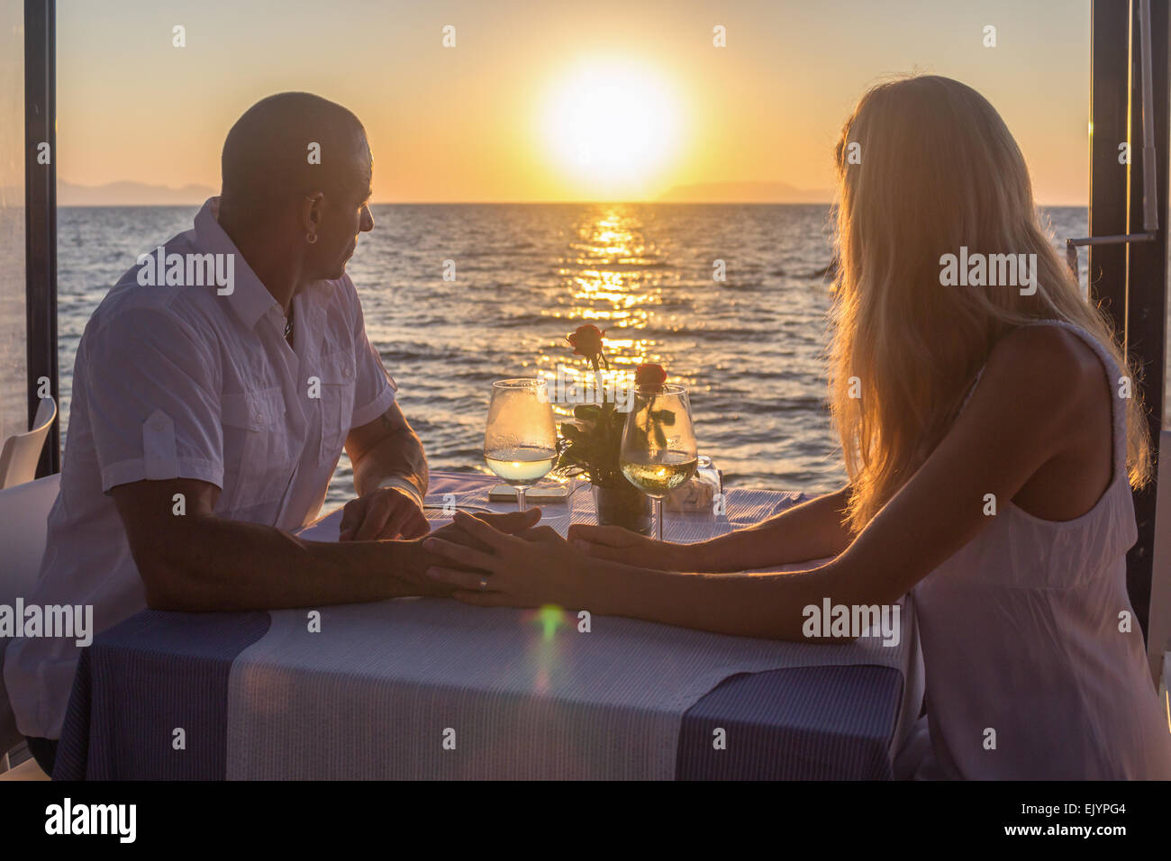 dating couple drinking silhouette sunset sun vacation summer sea restaurant Stock Photo