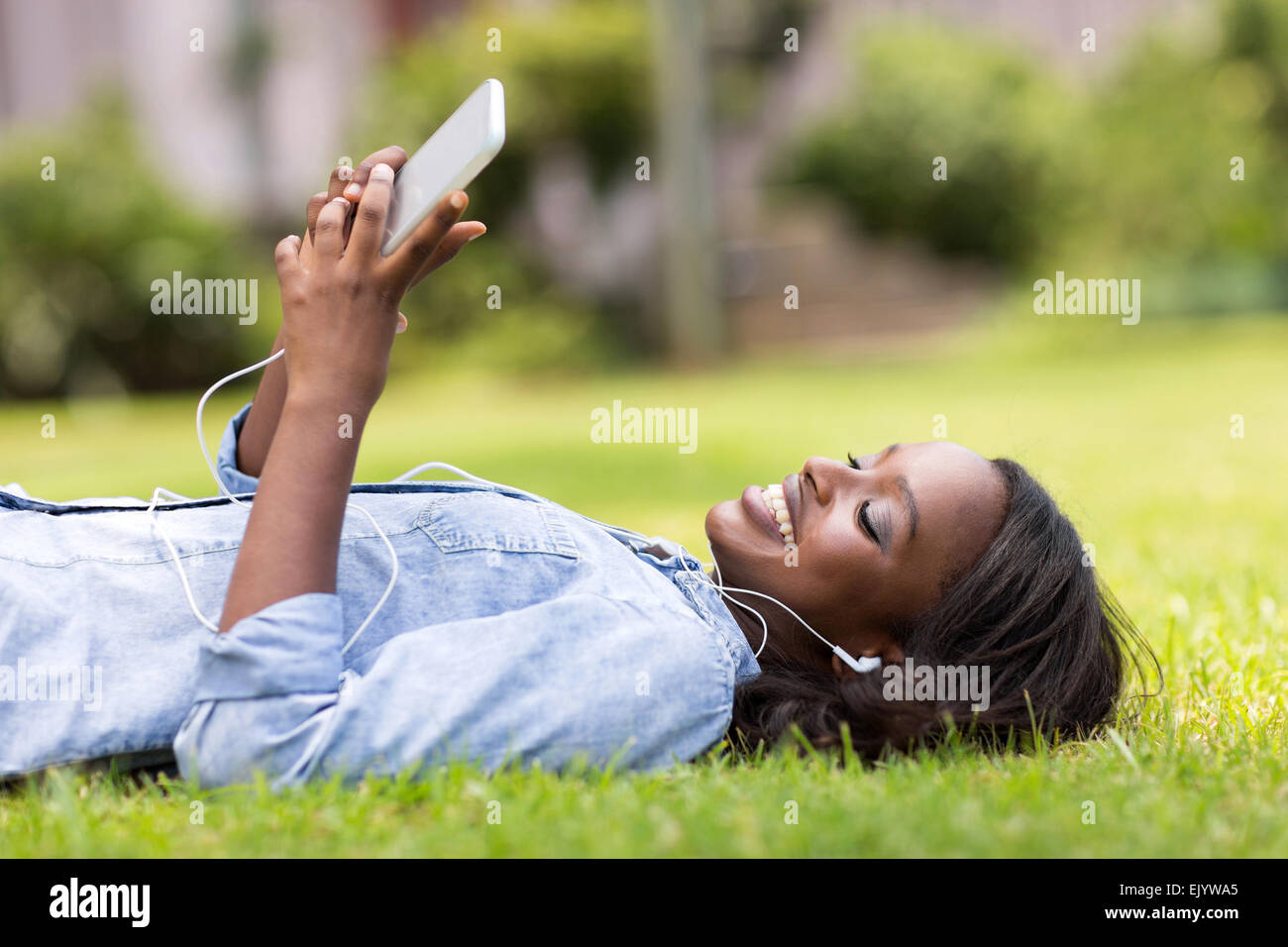 relaxed African woman lying on grass listening to music Stock Photo - Alamy