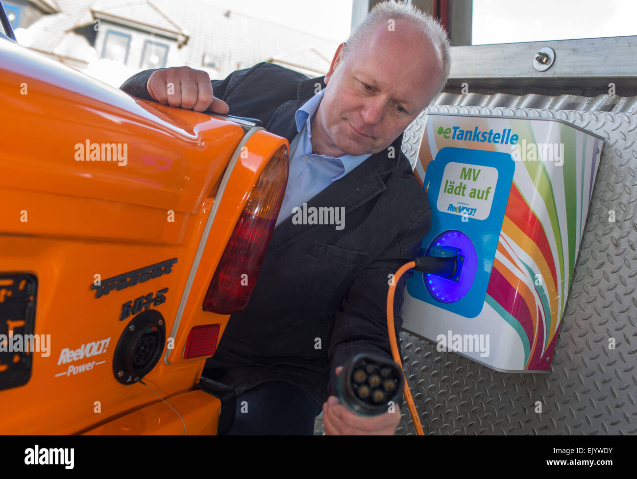 Schwerin, Germany. 12th Mar, 2015. Hans Busse plugs a cable into a Trabant (Trabi) car, which has been converted to run on electricity at a workshop in Schwerin, Germany, 12 March 2015. The E-Trabi is intended to be used for tourist safaris on the island of Ruegen in spring 2015. The firm ReeVolt converts existing vehicles to run on electricity. Photo: Jens Buettner/dpa/Alamy Live News Stock Photo
