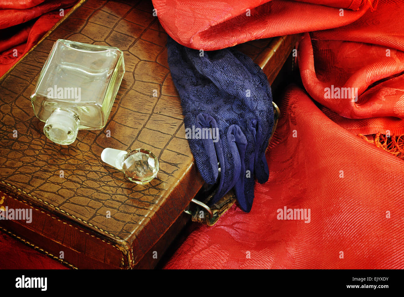 Bottle of perfume and leather bag on red textile Stock Photo