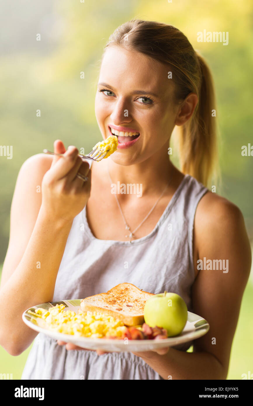 happy young woman eating scrambled eggs for breakfast Stock Photo Alamy