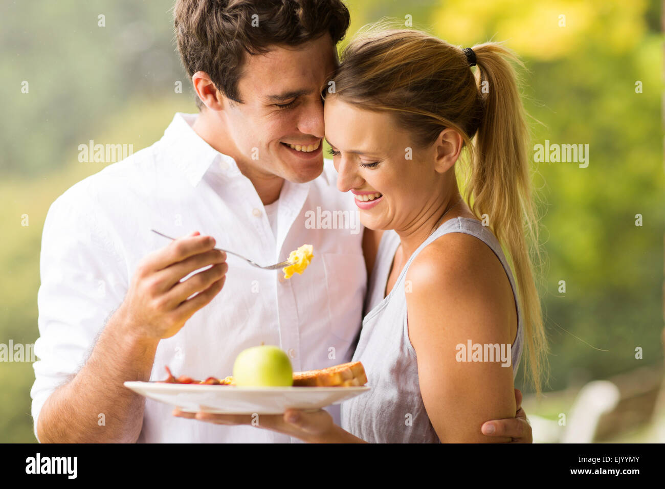 loving husband feeding wife breakfast outdoors Stock Photo