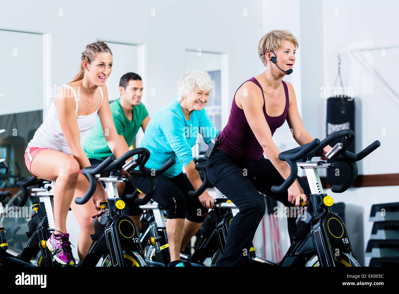 Senior and young people spinning on fitness bike in gym doing endurance