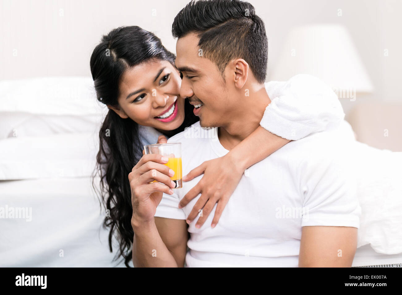 Asian couple, man and woman, embracing each other in bed Stock Photo