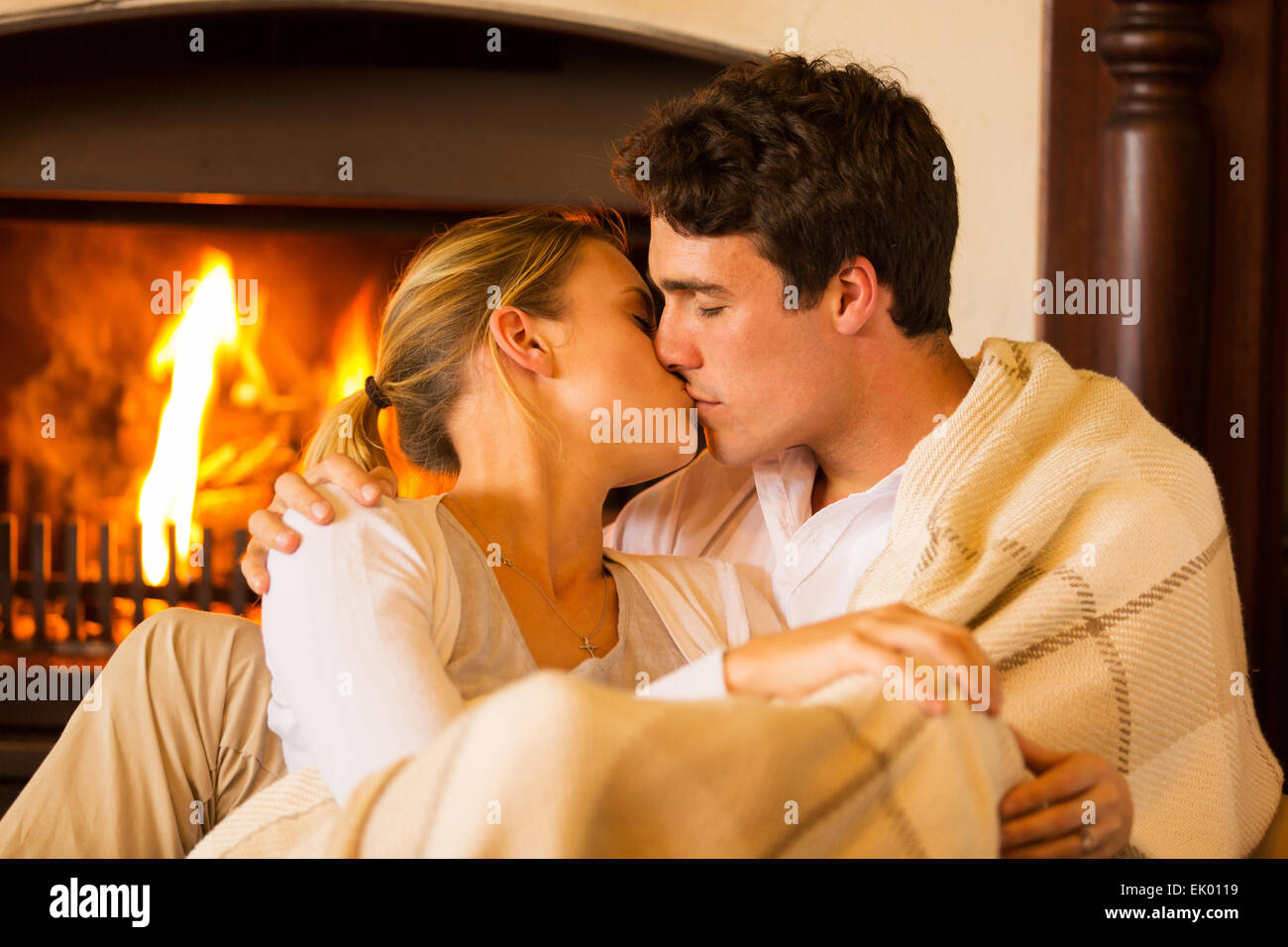 intimate young couple kissing at home in front of fireplace Stock Photo