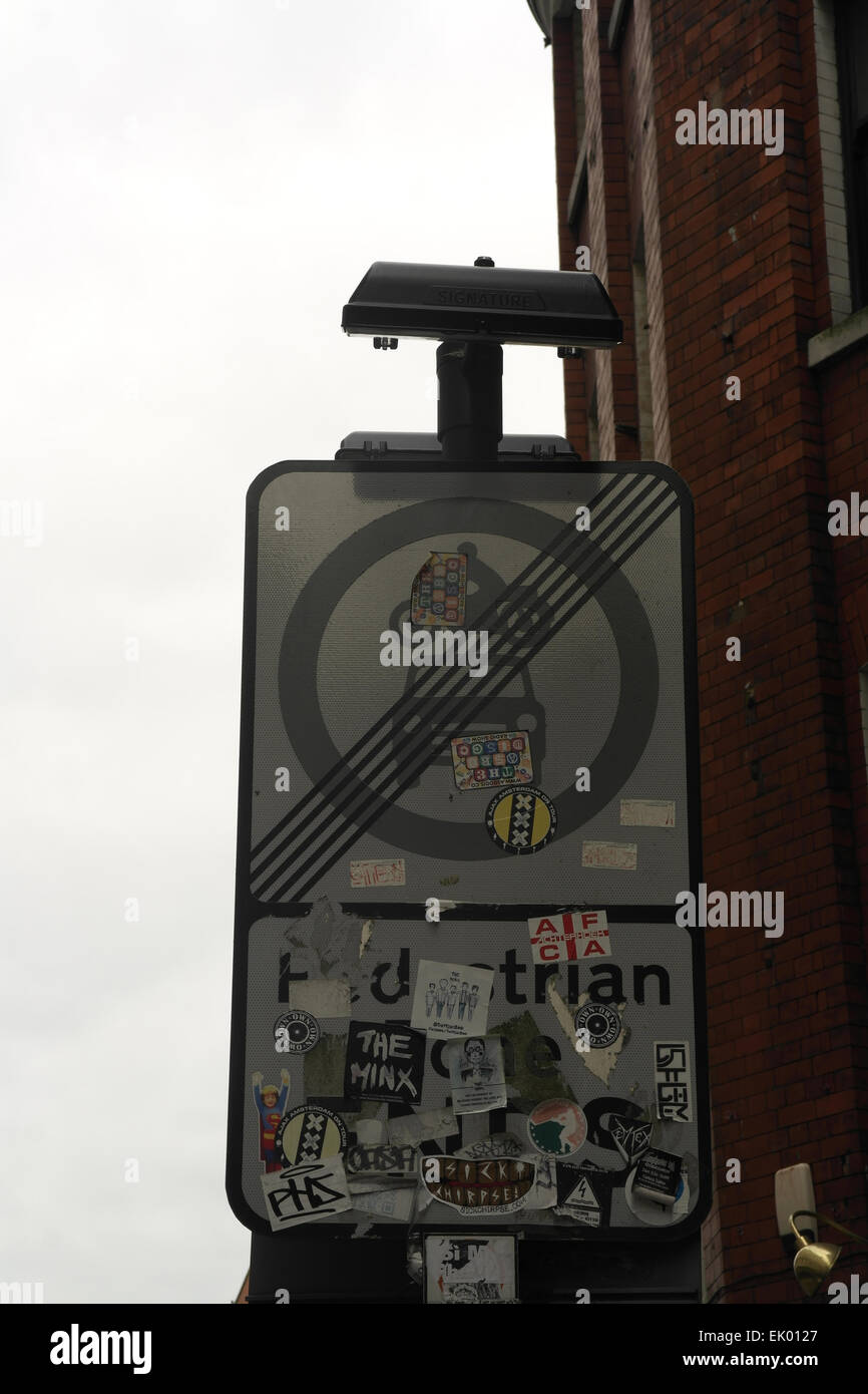 Grey sky portrait 'Pedestrian Zone Ends' road sign, with small graffiti stickers, Tib Street at Market Street, Manchester, UK Stock Photo