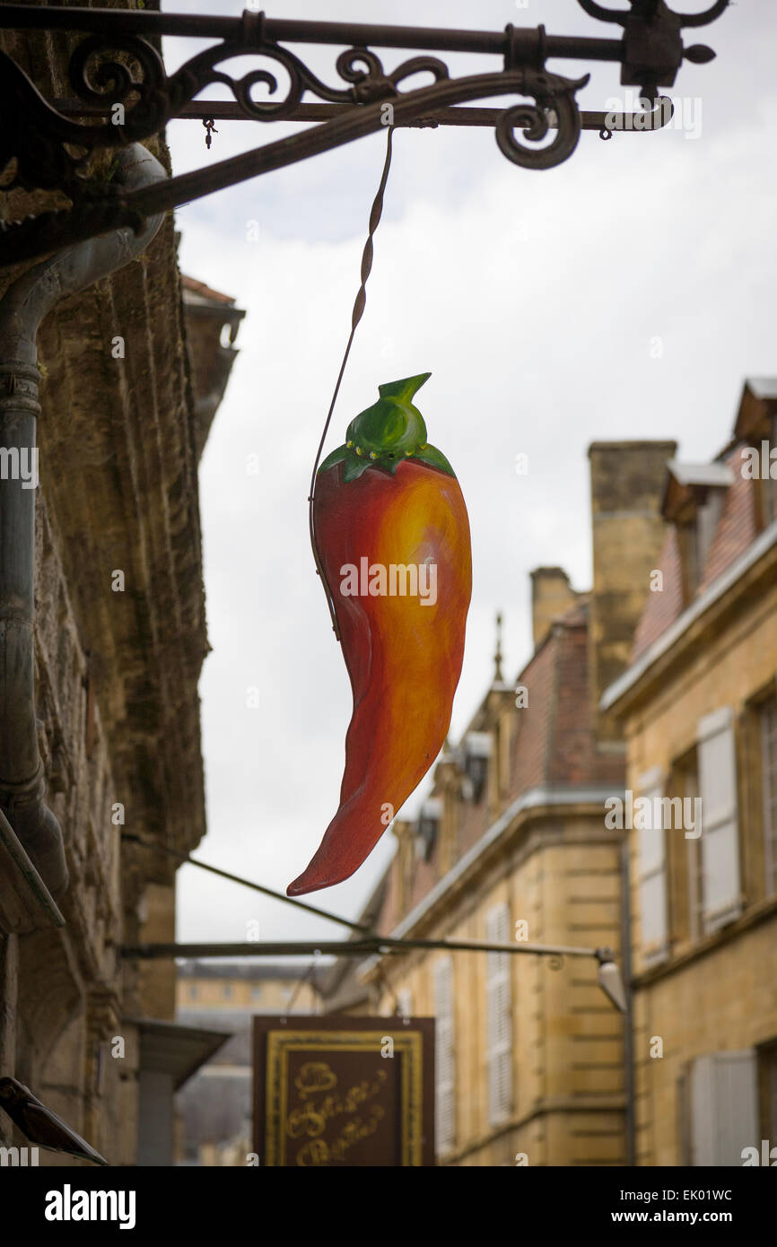 An ornate shop sign in the form of a carrot adds an artisitic influence to the street scene in Sarlat, Dordogne. Stock Photo