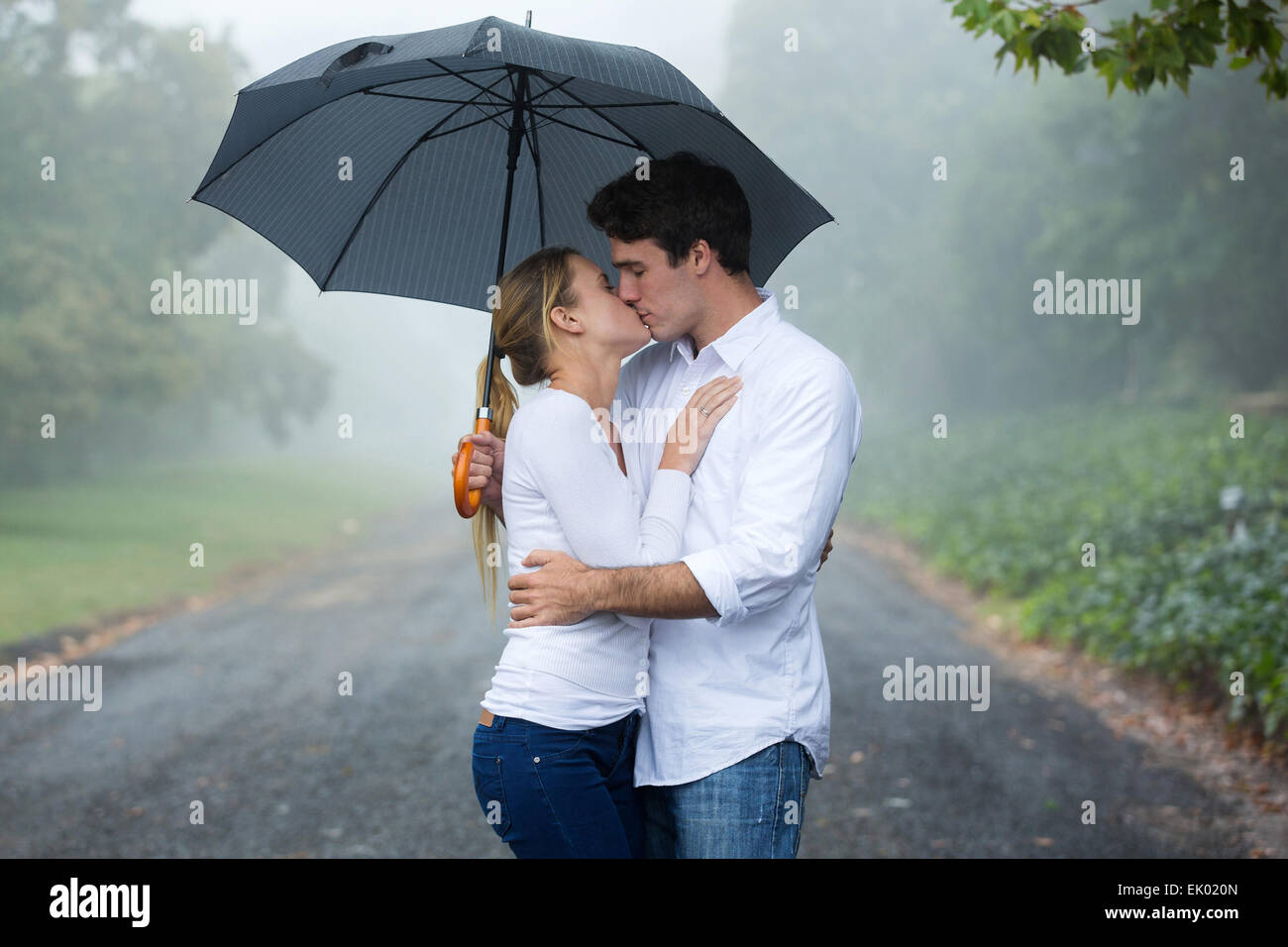 romantic couple kissing under an umbrella Stock Photo